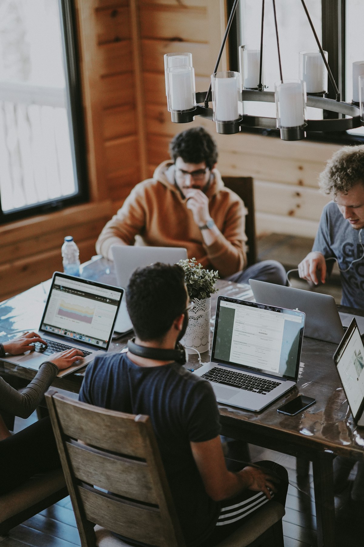Four people working on laptops around a wooden table